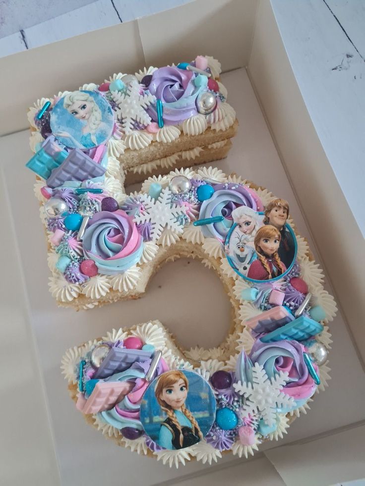 there is a birthday cake in the shape of the number five with princesses on it