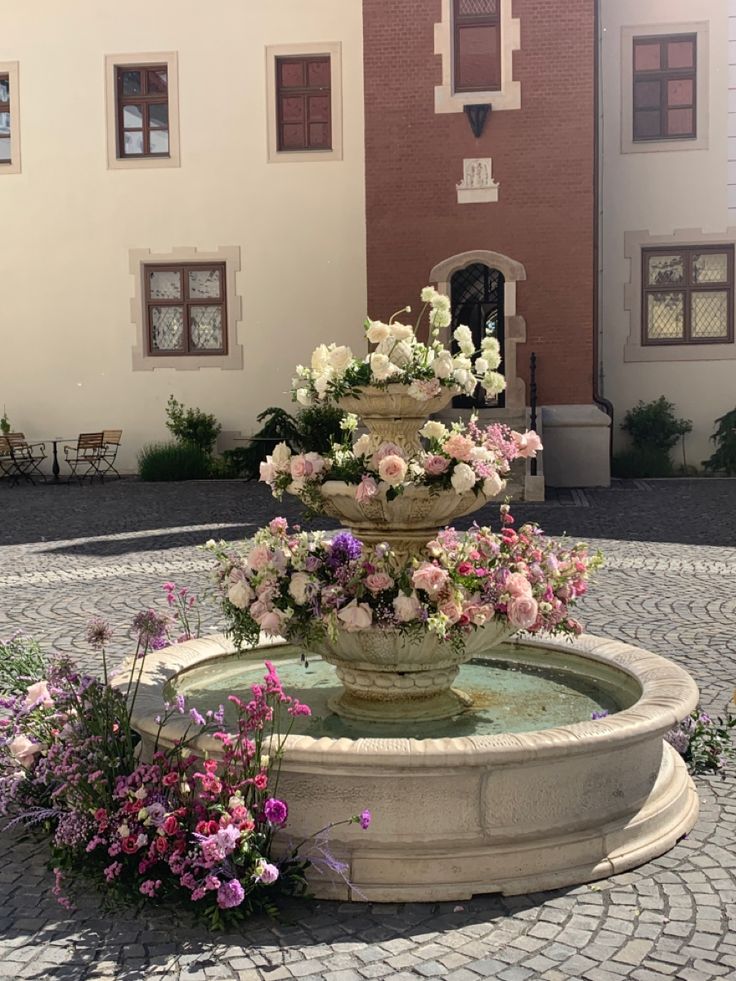 a fountain with flowers in front of a building