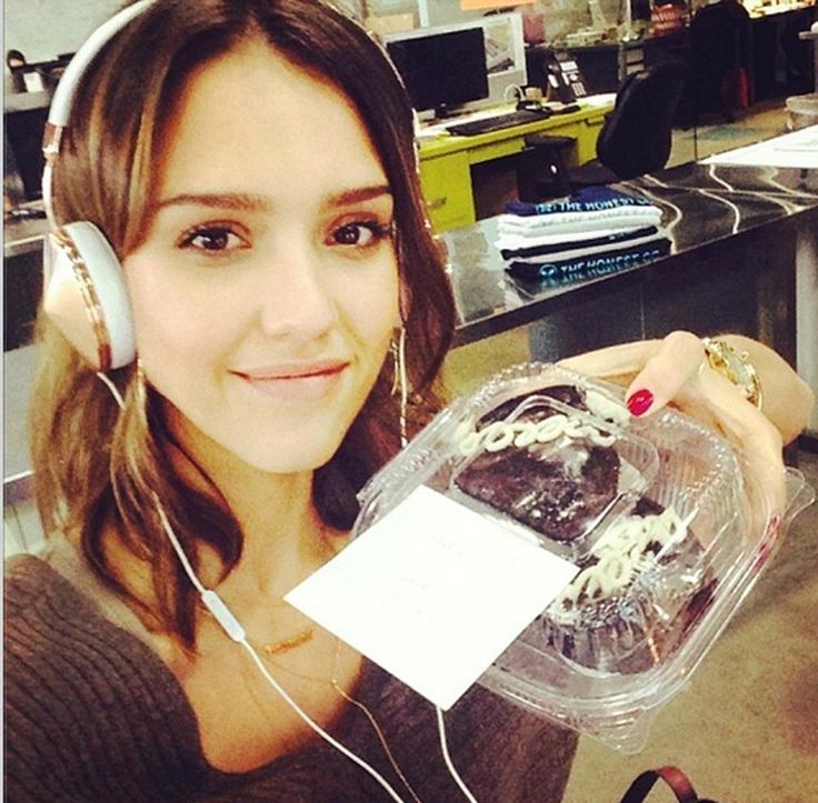 a woman holding up a plastic container with headphones on