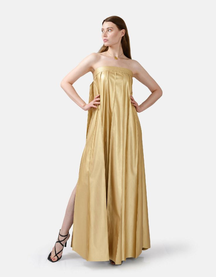 Chic, comfortable and edgy, this gold strapless pleated maxi dress offers a highly flexible fit with an adjustable button closure at back. Dress comes in ankle length or floor length, refer to size guide for dress length. High rise pleating, gold button details, and a stylistic belt tie at the bust add flare to the designs minimalist charm. The medium weight fabric, cruelty free vegan leather, has a loosely structured drape for a relaxed and remarkably comfortable fit. You'll be kept warm in coo Strapless Pleated Maxi Dress For Gala, Gala Maxi Dress With Folds, Gala Strapless Maxi Dress With Pleated Bodice, Gold Sleeveless Maxi Dress For Gala, Strapless Pleated Maxi Dress For Party, Summer Gala Strapless Pleated Dress, Summer Gala Pleated Strapless Dress, Pleated Strapless Dress For Summer Gala, Gold Strapless Dress For Gala