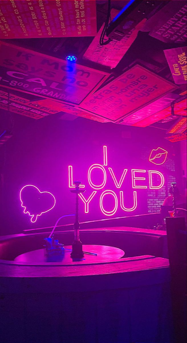 i love you neon sign in the middle of a room with purple lighting and tables