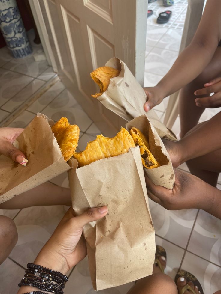 several people are sitting on the floor and eating food from paper bags in front of them