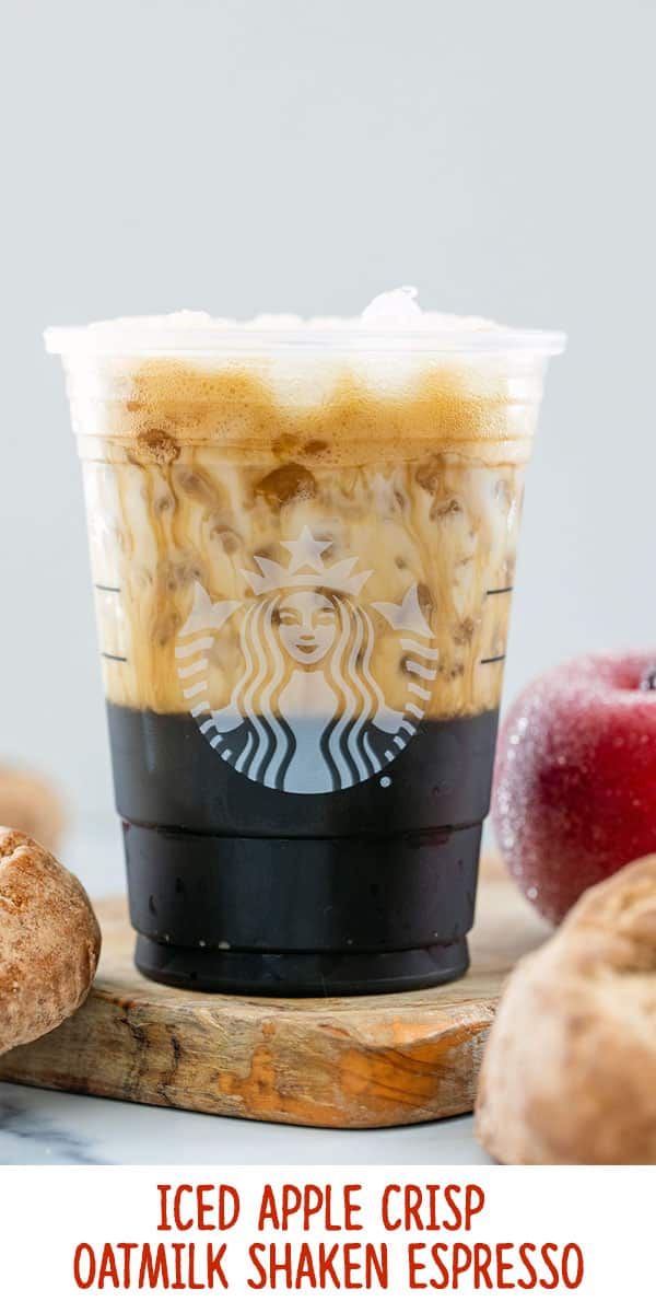 an iced apple crisp oatmeal shaker in front of fresh apples and cinnamon rolls