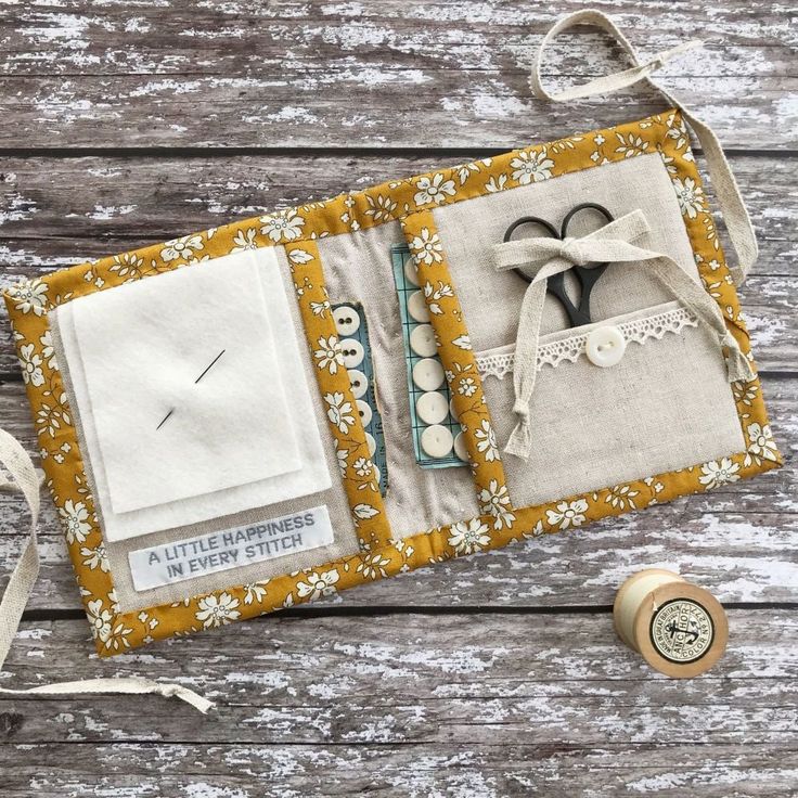 an open book with scissors and sewing supplies on top of wooden table next to thread spools