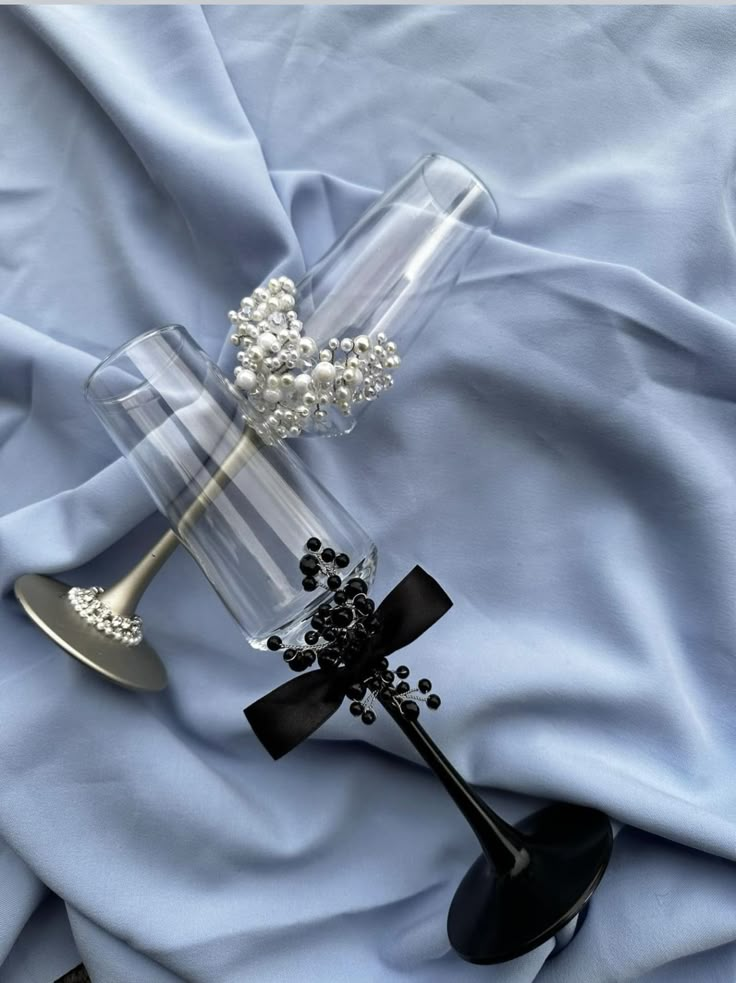 a glass vase with pearls and a cross on it sitting on a blue satin fabric