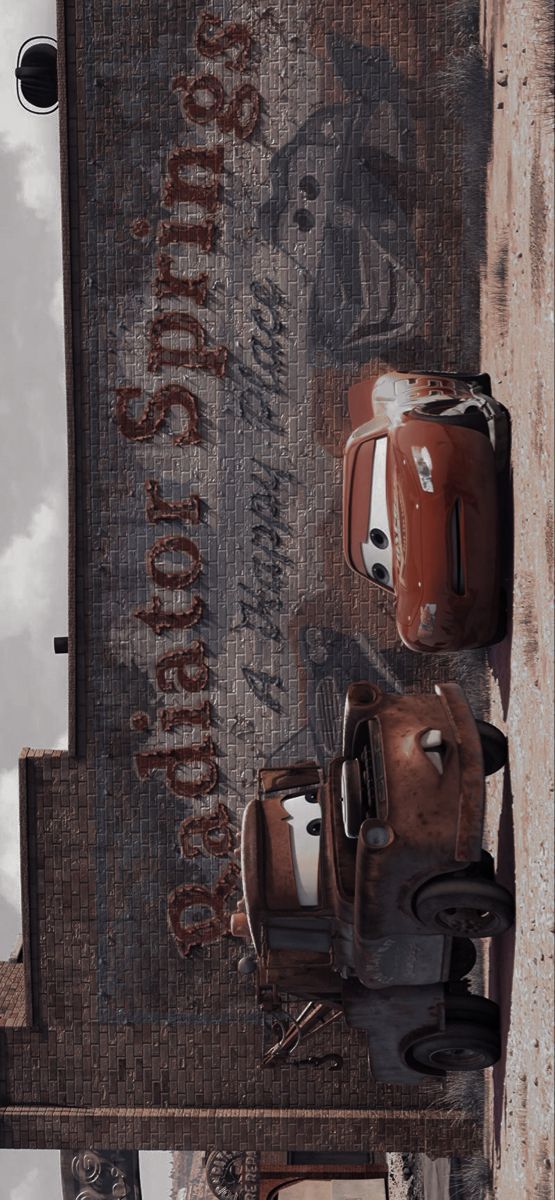 two old cars are parked in front of an old sign