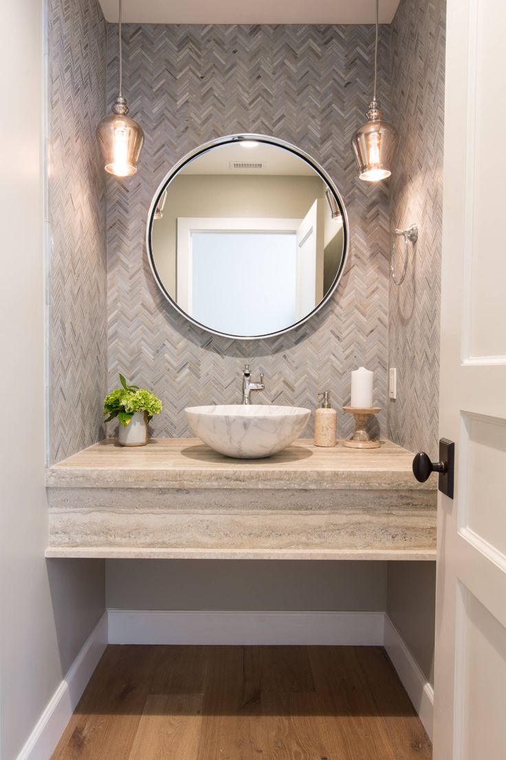 a bathroom vanity with a round mirror above it and lights on the wall next to it