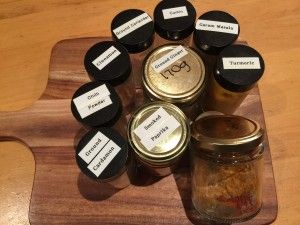 several jars with labels on them sitting on a cutting board next to a glass jar