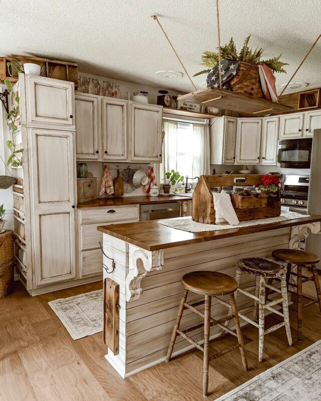 a kitchen with wooden floors and white cabinets, an island in the middle has two stools on it