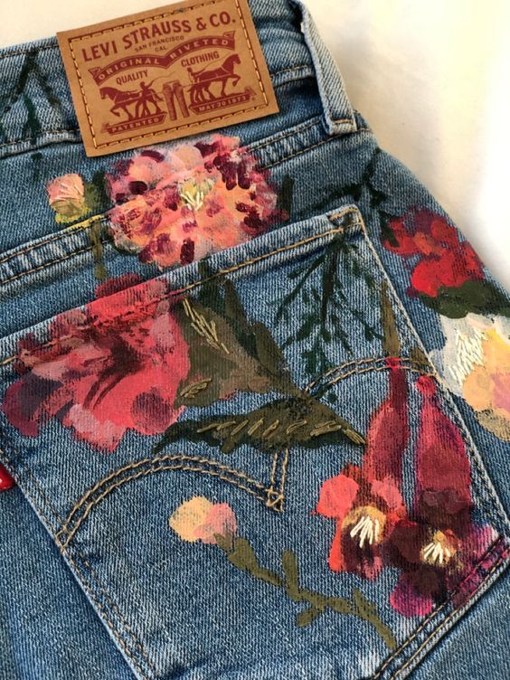 the back pocket of a pair of jeans with flowers painted on it and a leather tag