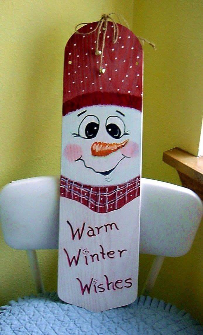 a wooden sign that says warm winter wishes on the front and back of it, with a snowman's face wearing a red hat