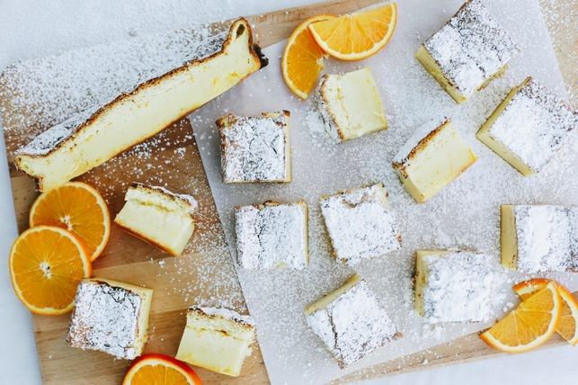 sliced oranges and pieces of cake on a cutting board with powdered sugar sprinkled on top