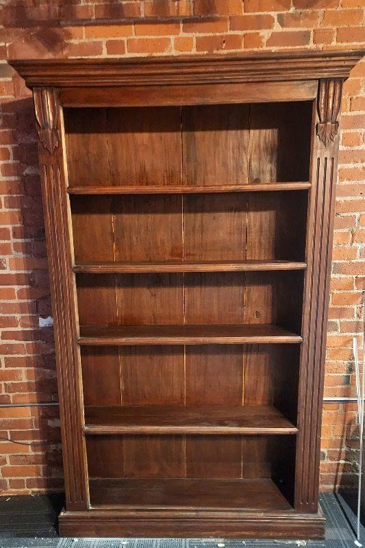 an old wooden bookcase in front of a brick wall