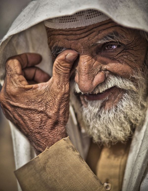 an old man is holding his head in one hand and looking at the camera with both hands