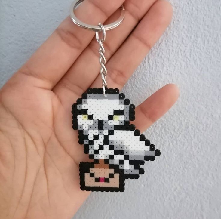 a hand holding a pixel keychain with an image of a sheep on it