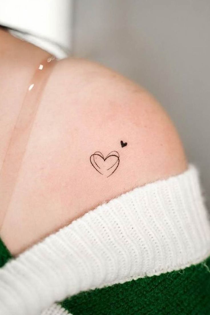 a woman with a small heart tattoo on her shoulder