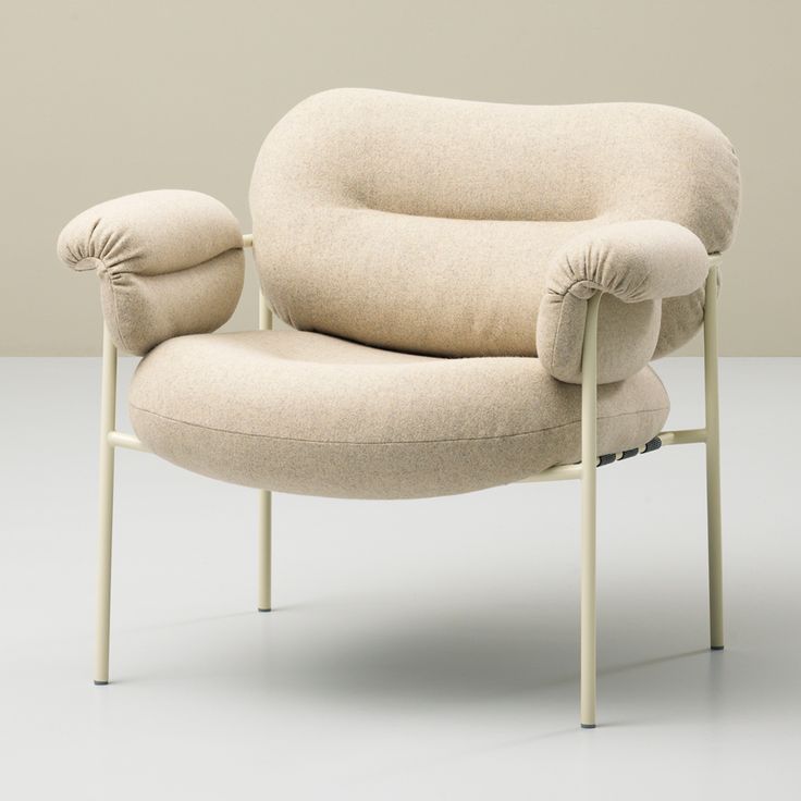 a beige chair with two pillows on it's back and armrests, in front of a white background