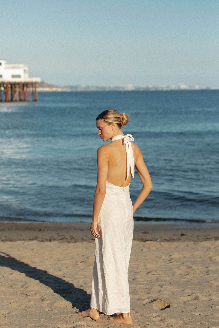 FINAL SALE. This white linen blend dress features a halter tie, perfect for summer evenings. Enjoy a sunset sip while looking effortlessly stylish. The breathable fabric blend ensures comfort and versatility for any occasion. Elegant Summer Halter Top With Tie Back, Elegant Backless Halter Top For Summer, Elegant Beach Halter Top, Elegant Halter Neck Top For Beach, Breezy Sleeveless Beach Dress For Beach Wedding, Sleeveless Breezy Beach Dress For Beach Wedding, Breezy Sleeveless Beach Dress For Wedding, Elegant Maxi Dress For Summer Parties, Chic Maxi Dress For Beach Wedding In Summer