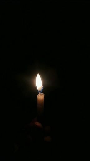 a candle is lit in the dark with only one light on it's side