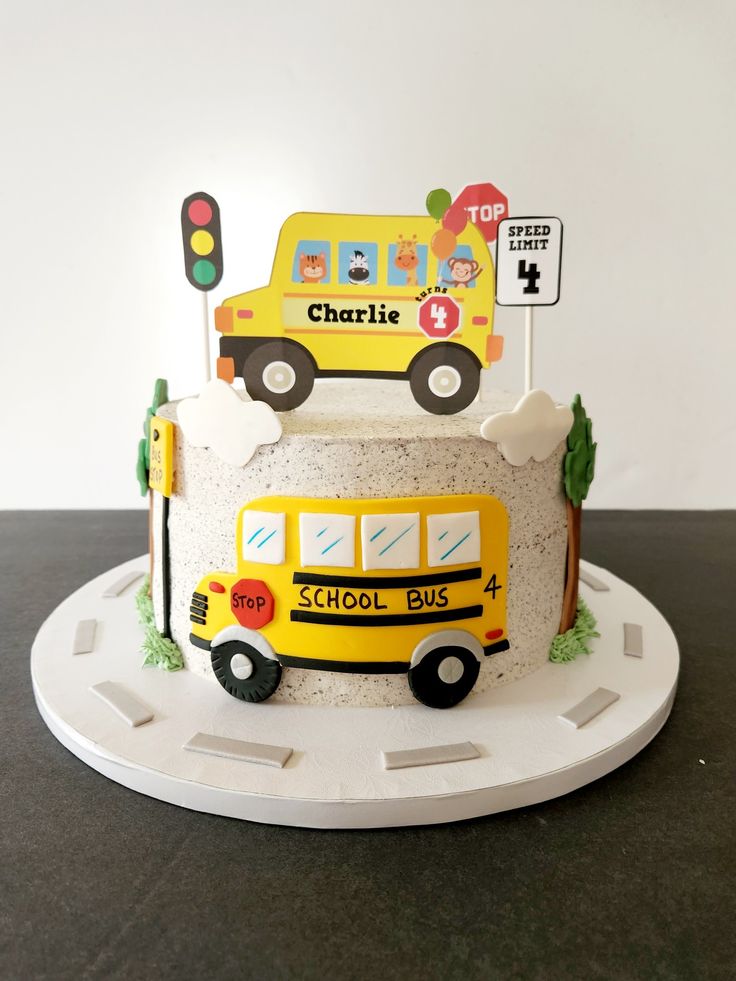 a yellow school bus cake sitting on top of a white plate next to a traffic light