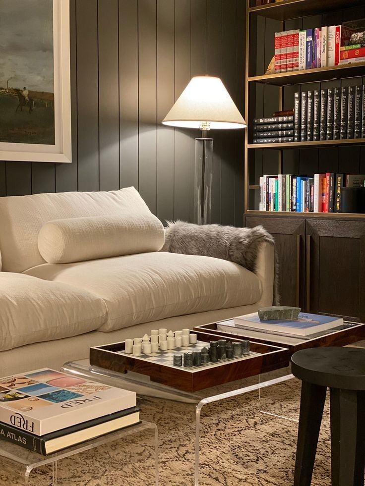 a living room filled with furniture and bookshelves next to a lamp on a table