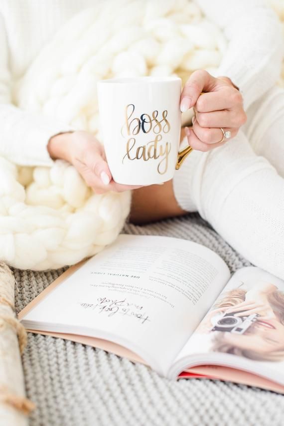 a woman holding a coffee mug while reading a book