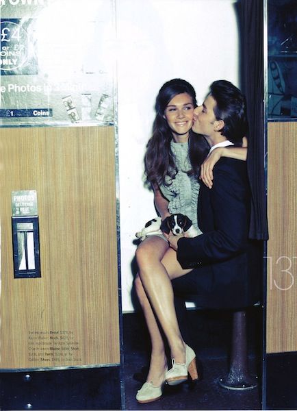 two women sitting on a bench kissing each other in front of a vending machine