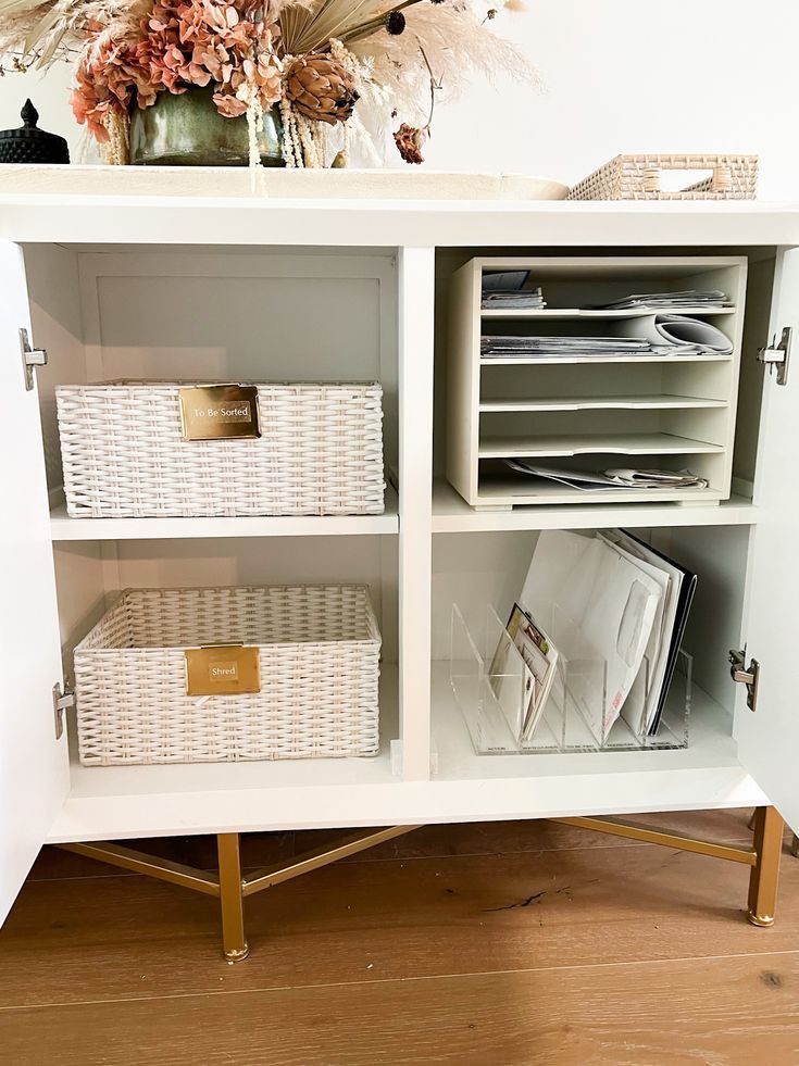 a white cabinet with wicker baskets and flowers