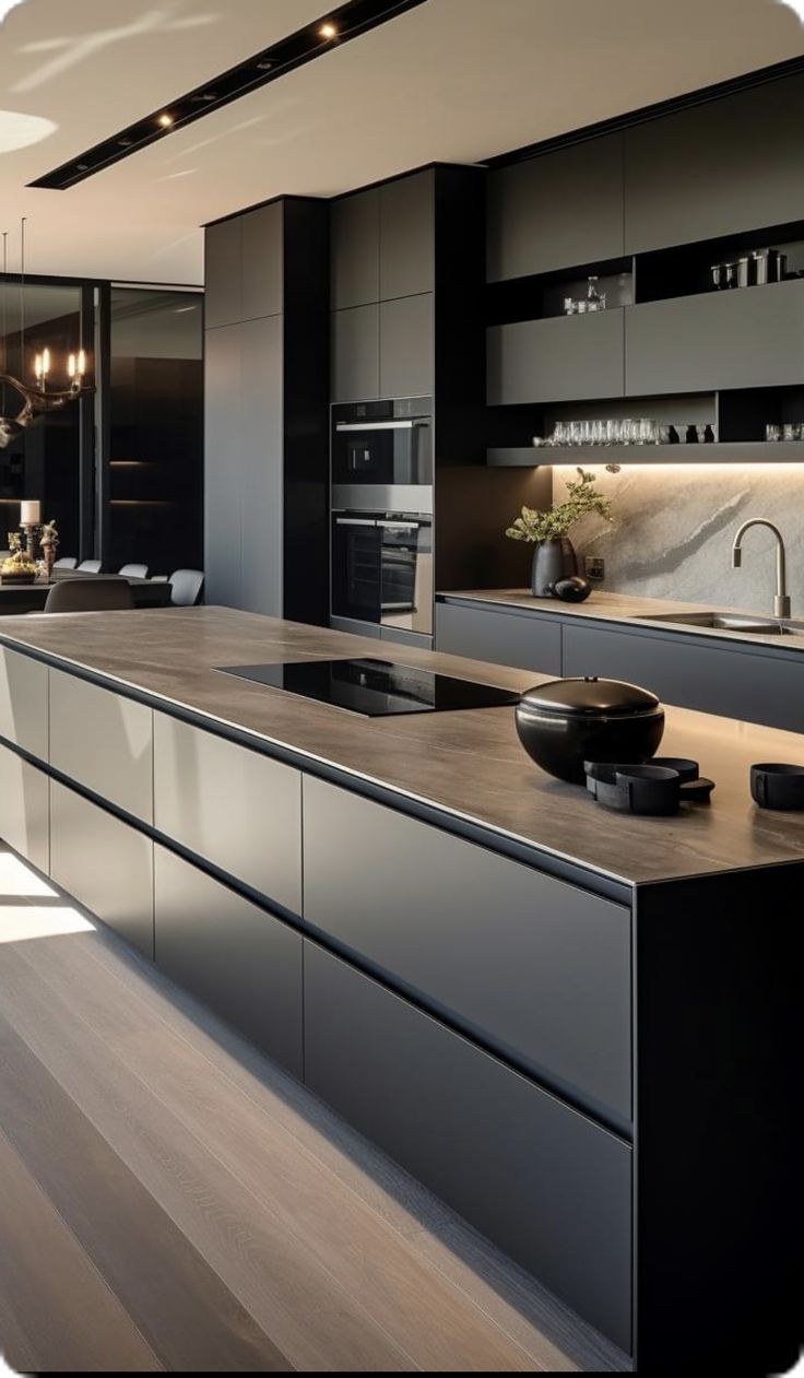 a modern kitchen with an island countertop and black cabinets in the center is lit by recessed lights