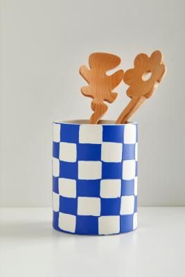 a blue and white checkered cup with two wooden spoons sticking out of it