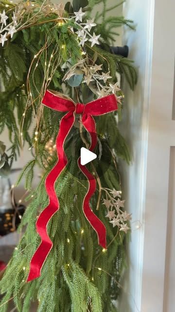 a christmas wreath hanging from the side of a door with red ribbon and snowflakes