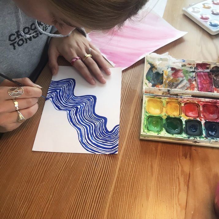 a woman is painting with watercolors on paper