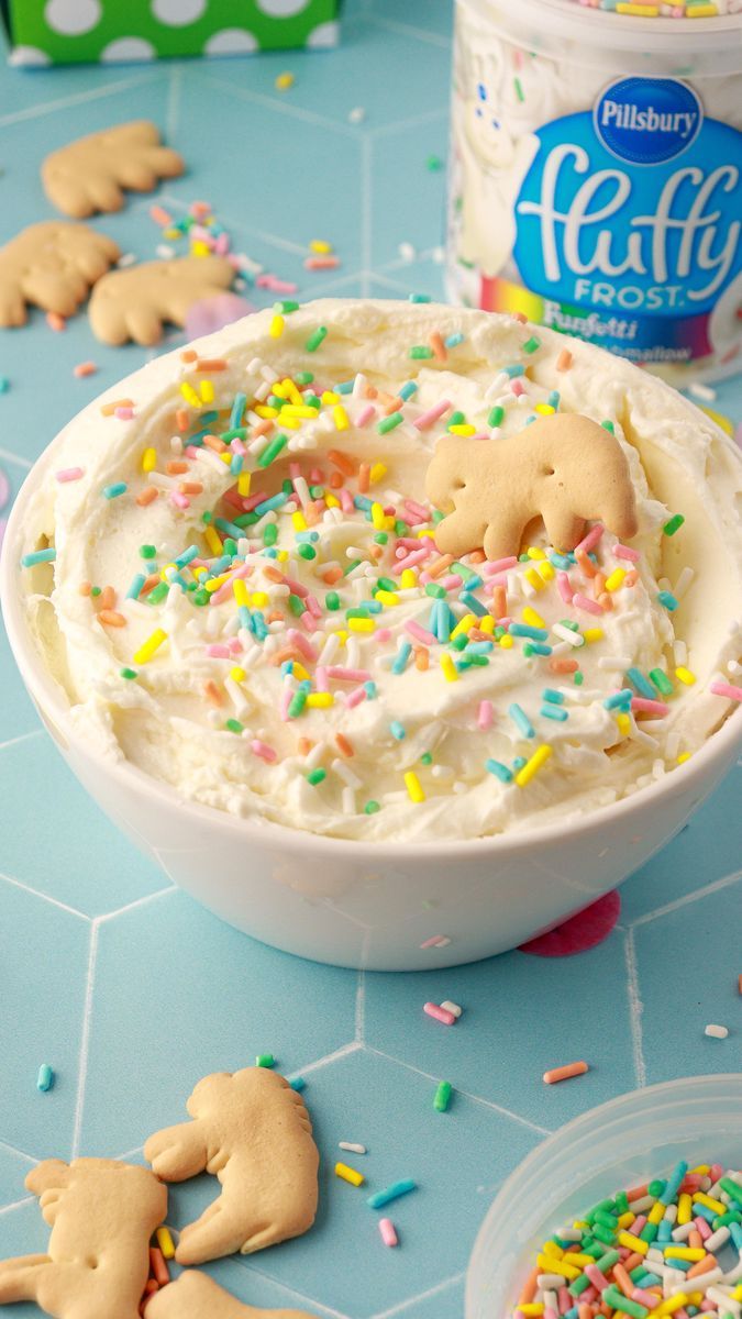 a bowl filled with frosting and sprinkles next to two cups of ice cream