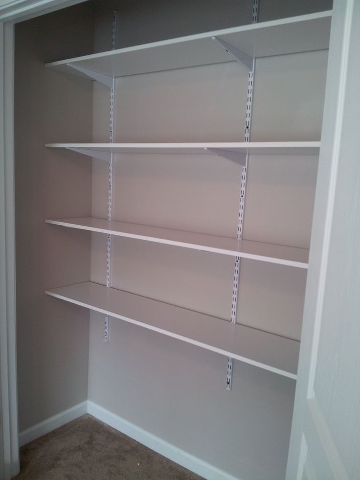 empty shelving unit in the corner of a room with carpeted floor and white walls