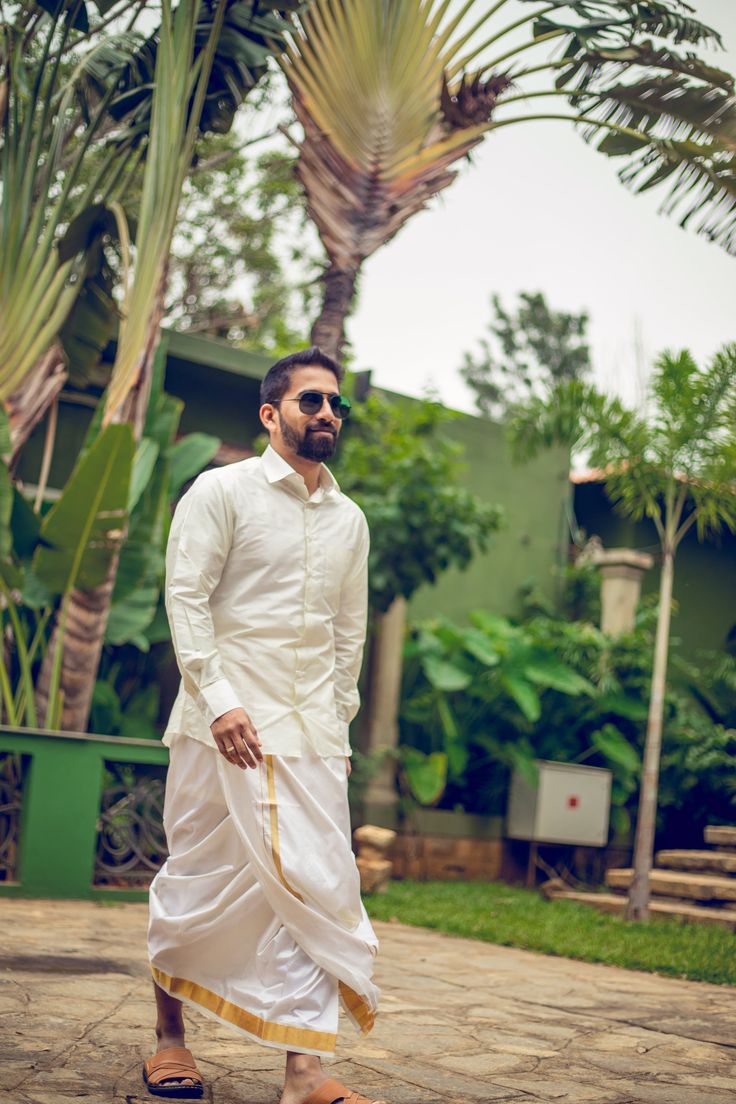 a man in white is walking down the street with his hand on his hip and sunglasses on