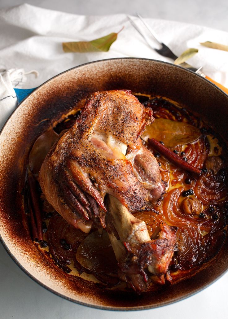 a large roasting pan filled with meat and vegetables on top of a white table