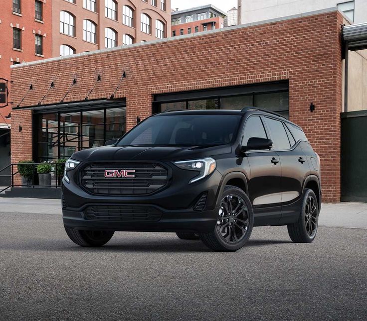 the gmc terrain suv is parked in front of a brick building