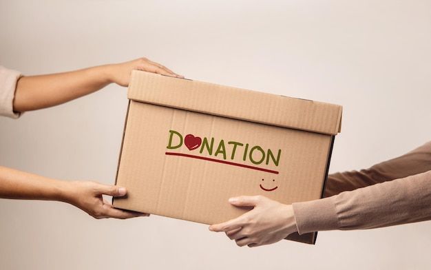 three people holding a box with the word donation written on it and two hands reaching out to each other