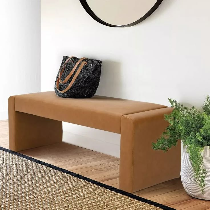 a brown bench sitting next to a plant in a room