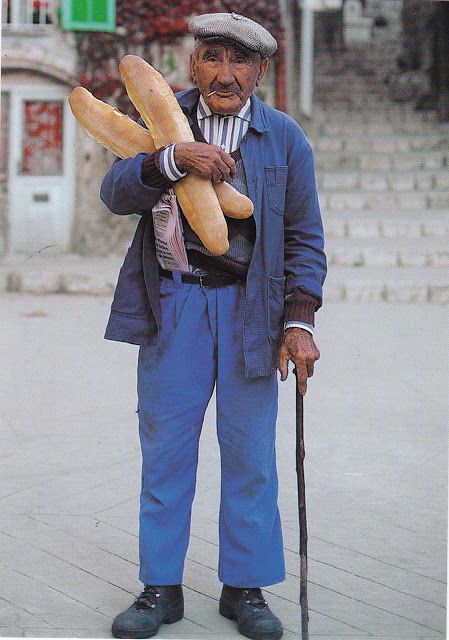 an old man holding two loaves of bread