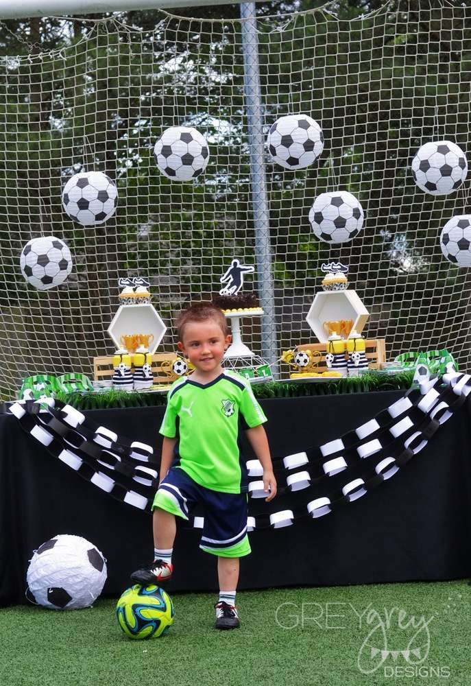 a young boy standing next to a soccer ball