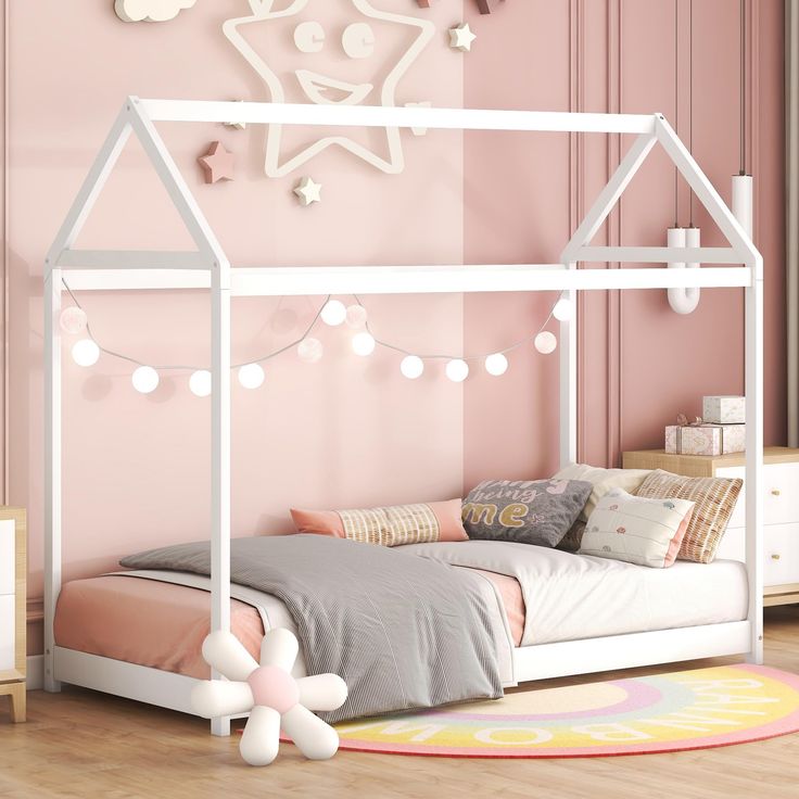 a bedroom with pink walls, white bed frame and string lights on the headboard