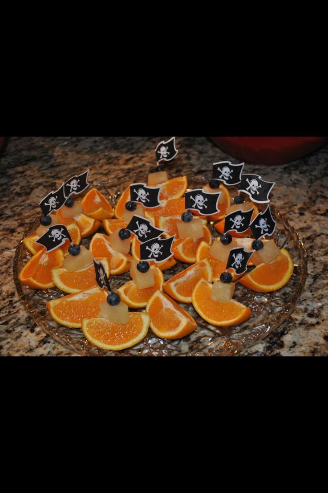 some orange slices are cut up and placed on a glass platter with pirate flags