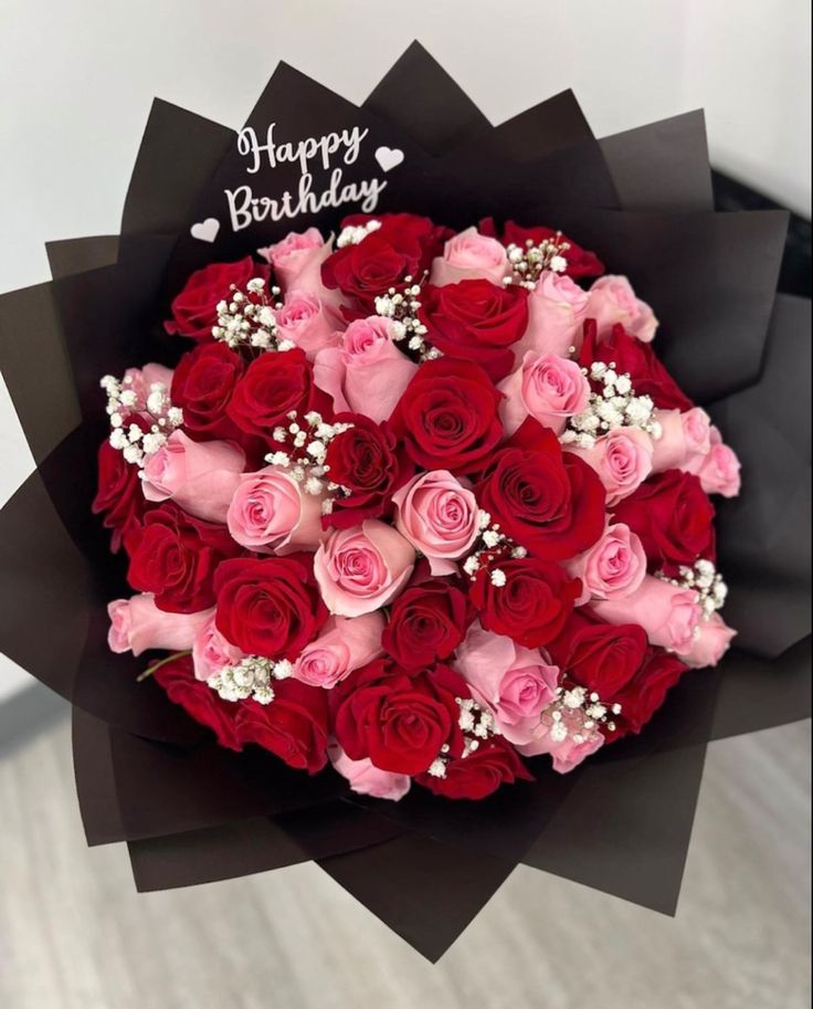 a bouquet of red and pink roses with happy birthday written on the top in black paper