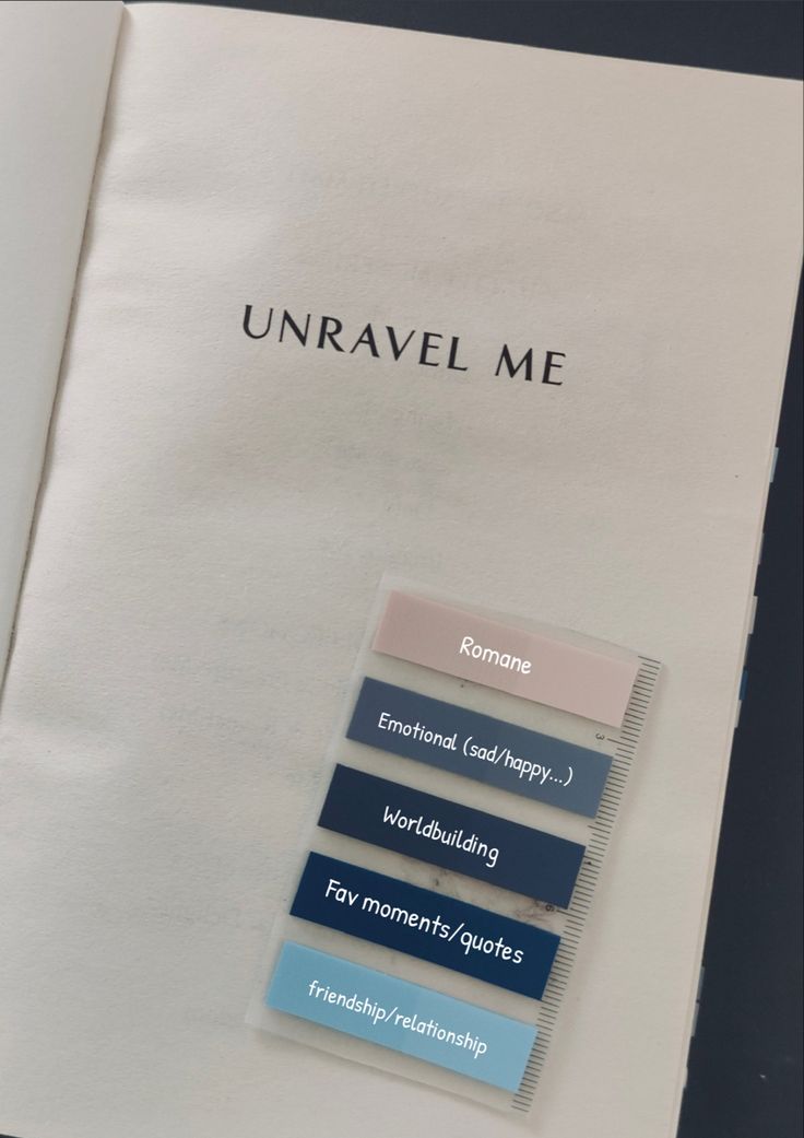 an open book with several different colored labels on the pages, including one that says unravel me