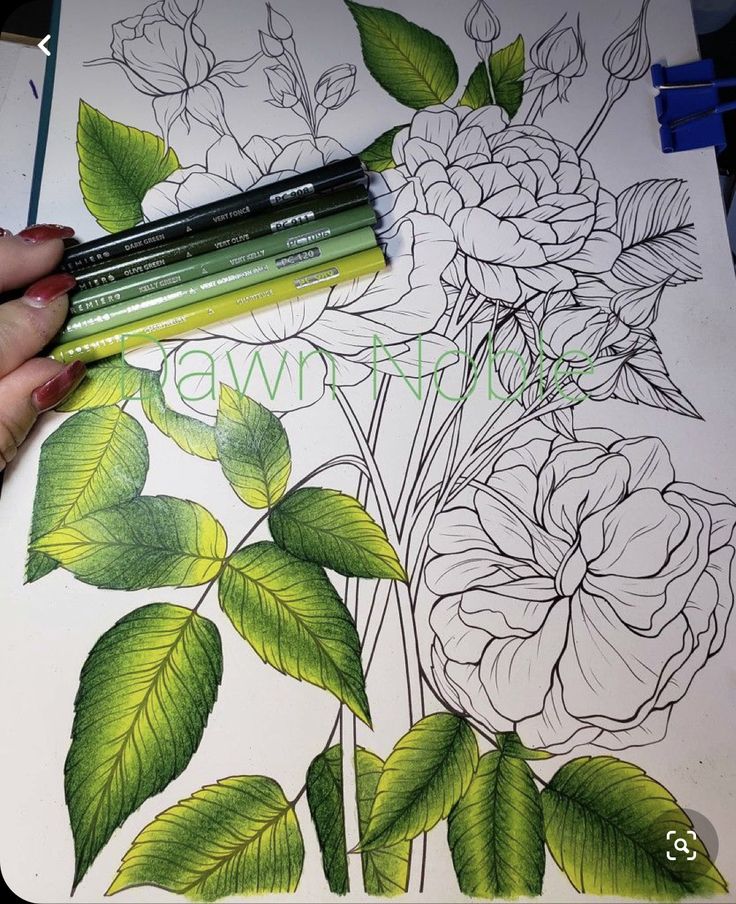 a person is drawing flowers on a sheet of paper with colored pencils and markers