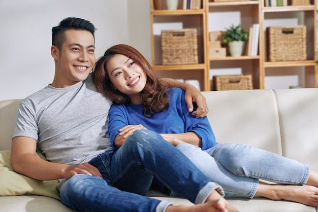 a man and woman sitting on top of a white couch