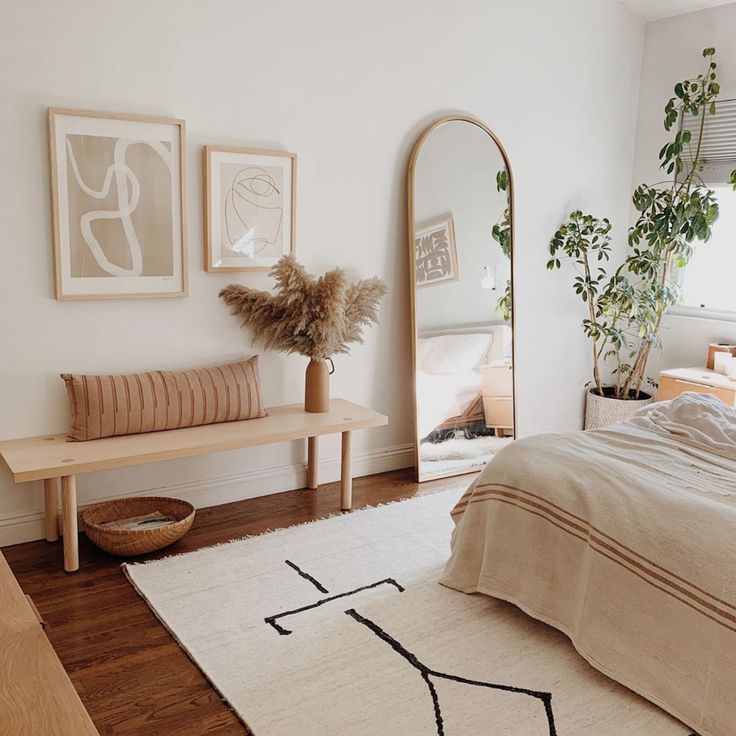 a bed room with a neatly made bed next to a large mirror and wooden furniture