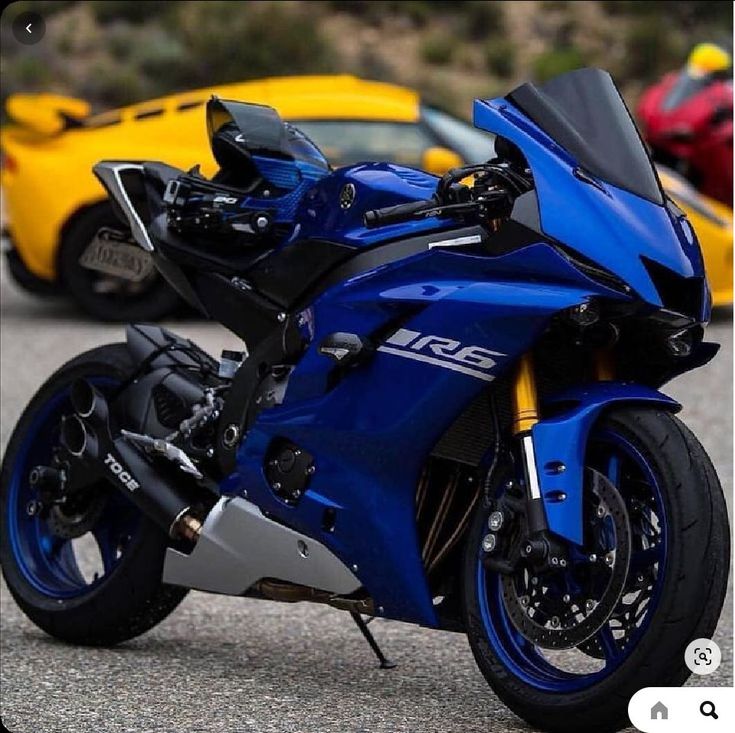 a blue motorcycle parked next to two yellow cars