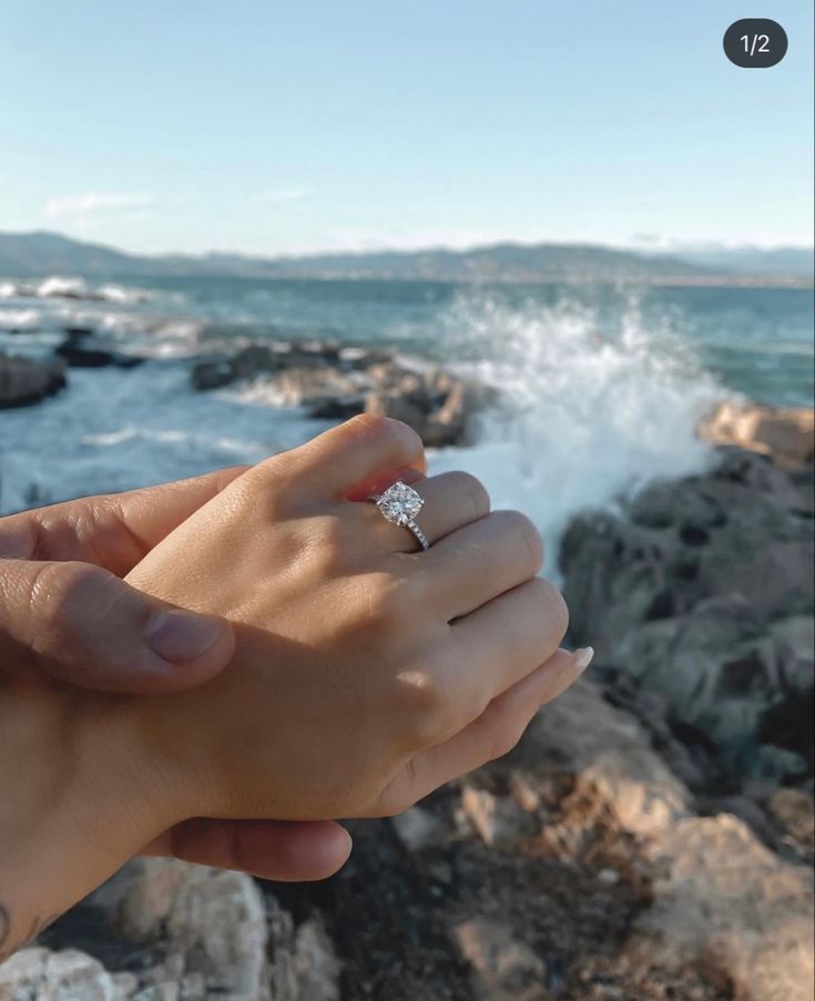 two people holding each other's hands near the ocean